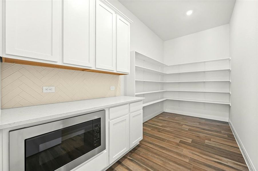 Massive walk-in pantry with prep area on the countertop with overhead cabinets and a microwave drawer. Doesn't get any better than this.