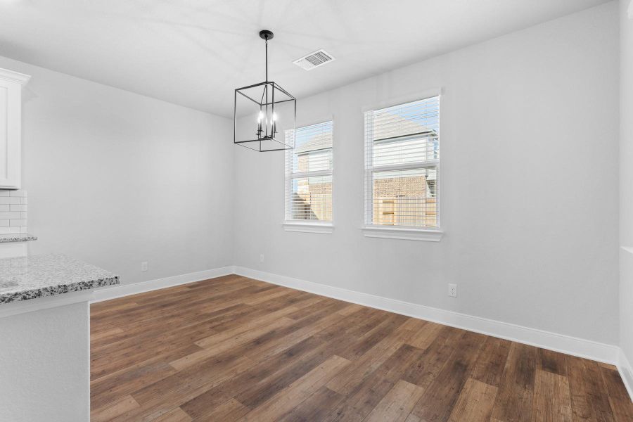Hardwood-style flooring extends across this naturally illuminated dining area, complemented by a modern geometric chandelier. Hardwood-style flooring extends across this naturally illuminated dining area, complemented by a modern geometric chandelier.