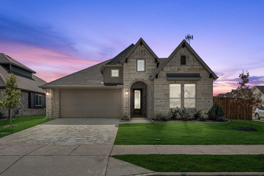 Stone and brick single-story home with arched entry, two-car garage, and manicured front lawn at dusk. Stone and brick single-story home with arched entry, two-car garage, and manicured front lawn at dusk.