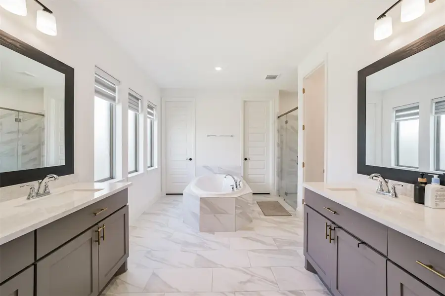 Spacious primary bedroom featuring a luxurious soaker tub and dual vanities, thoughtfully designed for both comfort and convenience. Spacious primary bedroom featuring a luxurious soaker tub and dual vanities, thoughtfully designed for both comfort and convenience.