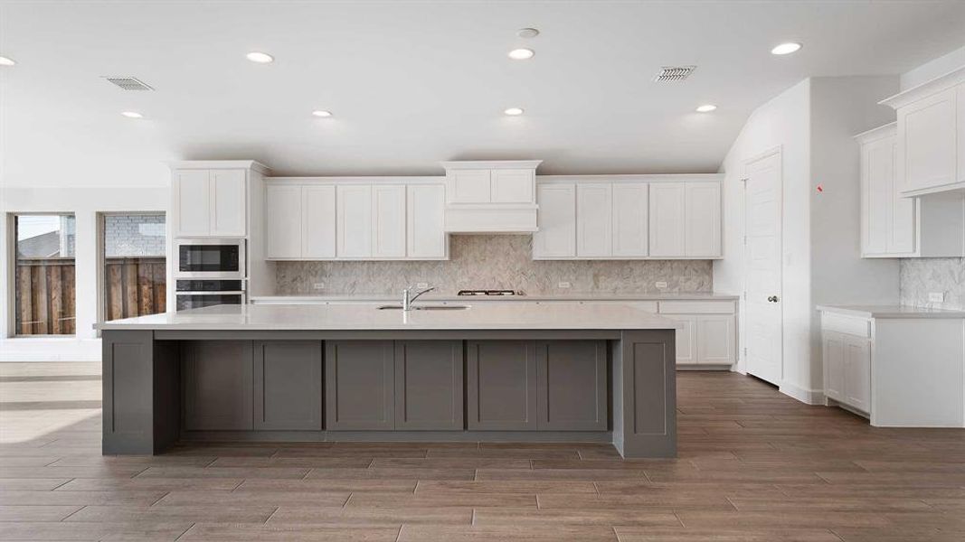 Kitchen featuring white cabinets, backsplash, oven, and black microwave