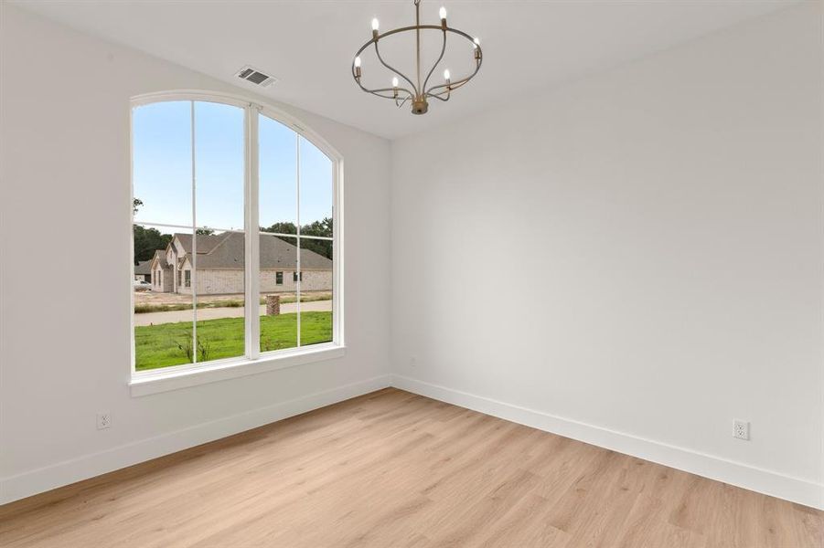 Spare room featuring light wood-type flooring and a chandelier