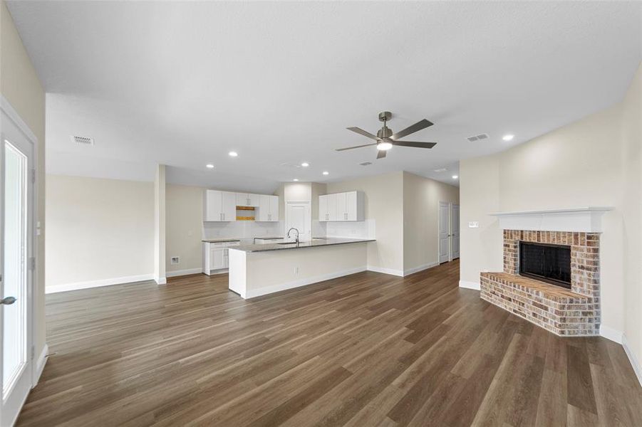 Spacious open-concept living area featuring wood-finish flooring, a contemporary ceiling fan, and recessed lighting