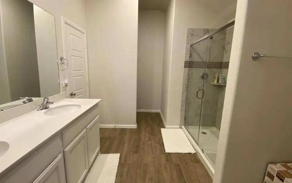 Full bath with a shower stall, dark wood-style floors, and double vanity Full bath with a shower stall, dark wood-style floors, and double vanity