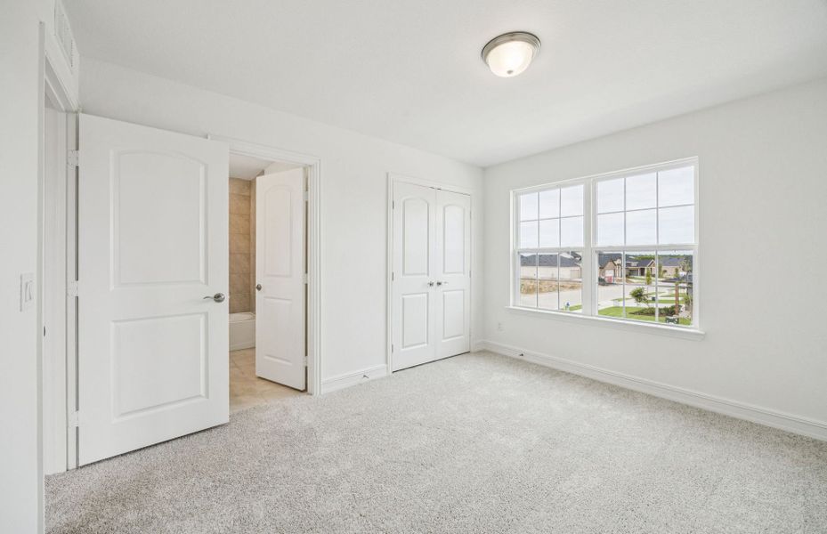 Roomy secondary bedroom with extensive closet storage  *Real home pictured
