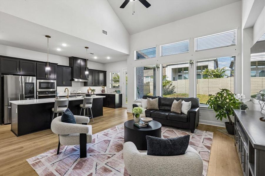 Vaulted ceiling living area featuring wood-finish flooring and a wall of windows Vaulted ceiling living area featuring wood-finish flooring and a wall of windows