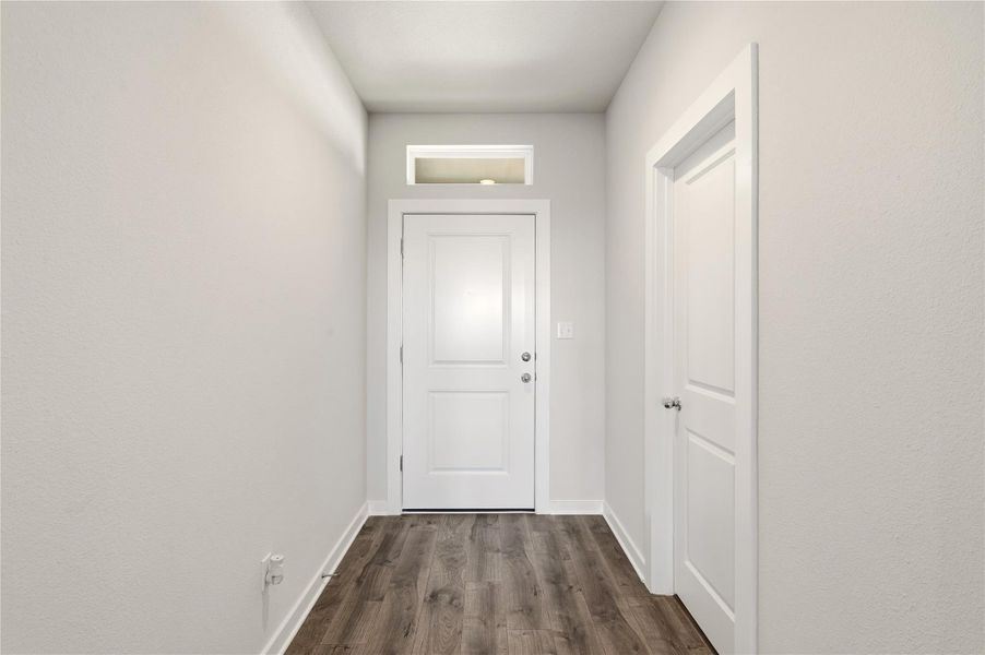 Doorway to outside with wood finished floors and baseboards