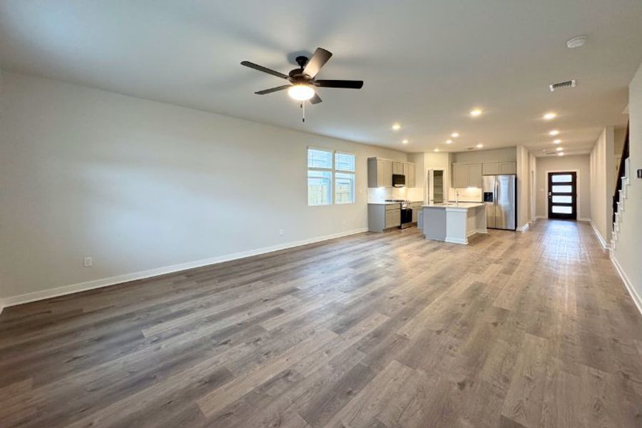 A large empty room with a ceiling fan and a wood floor. A large empty room with a ceiling fan and a wood floor.