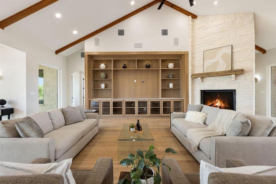 Living room featuring beamed ceiling, high vaulted
ceiling, arched walkways, a stone fireplace, and
light wood-style flooring Living room featuring beamed ceiling, high vaulted
ceiling, arched walkways, a stone fireplace, and
light wood-style flooring