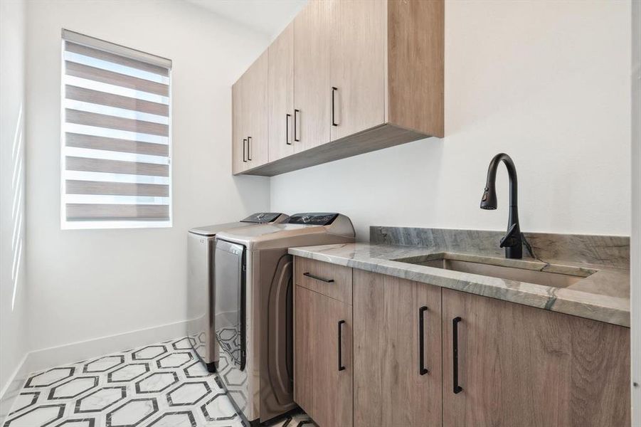 Clothes washing area featuring washing machine and clothes dryer, sink, cabinets, and light tile patterned floors