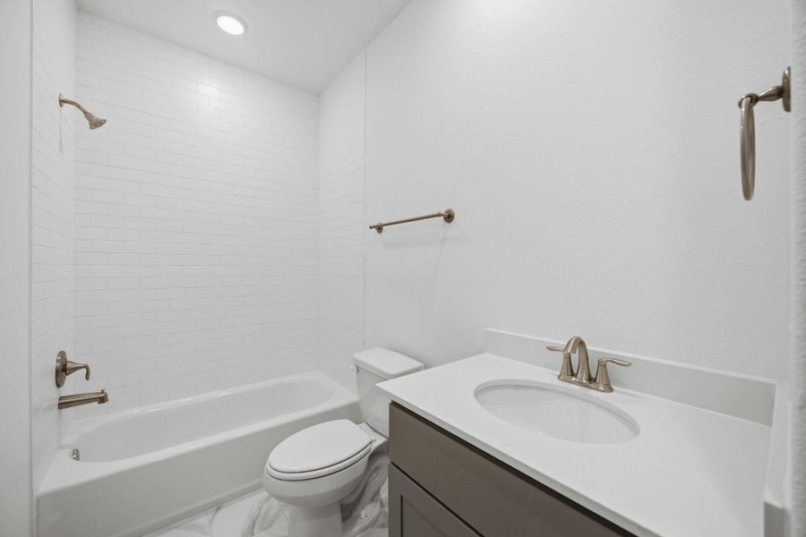 Chic & Functional. An example of a well-appointed secondary bath features stylish dark tile, quartz counters, and Moen fixtures.