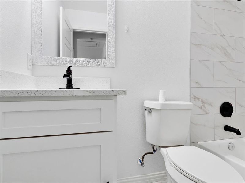 Bathroom featuring a white vanity with shaker-style cabinetry, a speckled countertop, and a black-finish faucet