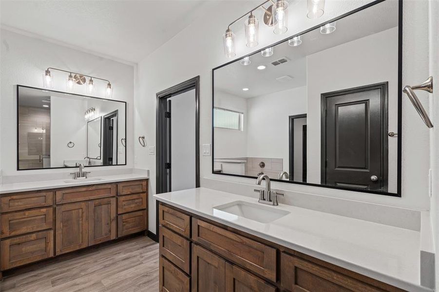 Full bath featuring wood finished floors and two vanities