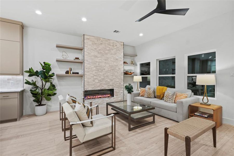 Living room featuring a stone fireplace, light hardwood / wood-style floors, and ceiling fan