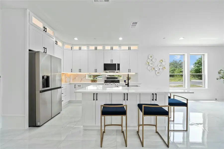 Kitchen featuring stainless steel appliances, light countertops, a kitchen bar, and recessed lighting