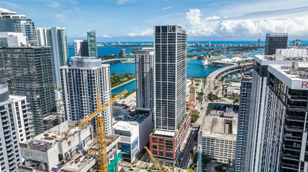 Aerial perspective of an urban high-rise landscape featuring glass-facade skyscrapers, waterfront exposure, and extensive bridge infrastructure