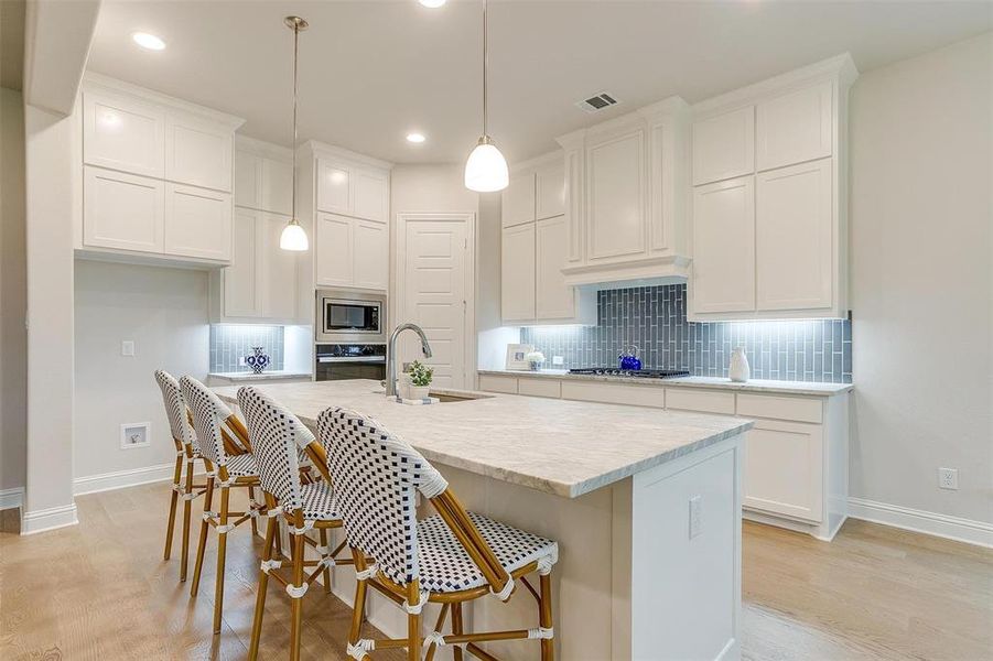 Kitchen with sink, tasteful backsplash, a center island with sink, white cabinetry, and appliances with stainless steel finishes