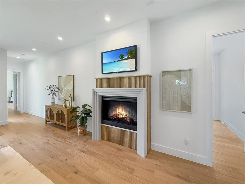 Living area featuring light wood-type flooring, a lit fireplace, and recessed lighting Living area featuring light wood-type flooring, a lit fireplace, and recessed lighting
