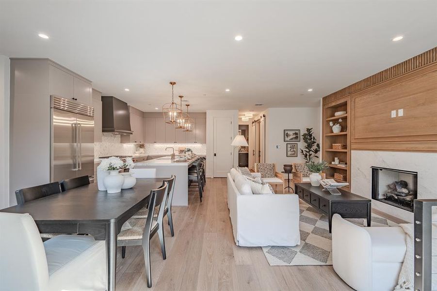 Dining area featuring a high end fireplace, light wood-style flooring, recessed lighting, a chandelier, and built in features Dining area featuring a high end fireplace, light wood-style flooring, recessed lighting, a chandelier, and built in features