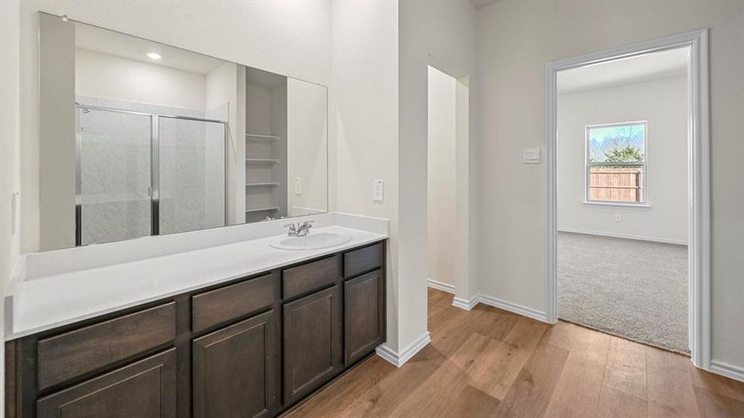 Vanity with integrated sink and chrome faucet, set against a large wall-mounted mirror