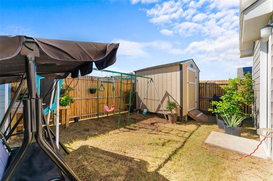Fenced backyard with a shed and a playground Fenced backyard with a shed and a playground