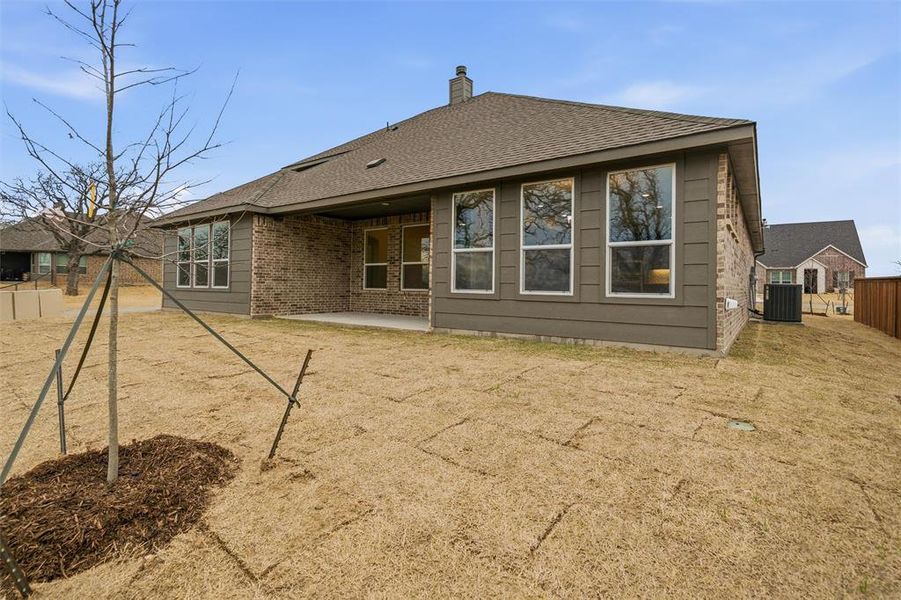 Rear view of property with a patio area, roof with shingles, a chimney, and brick siding