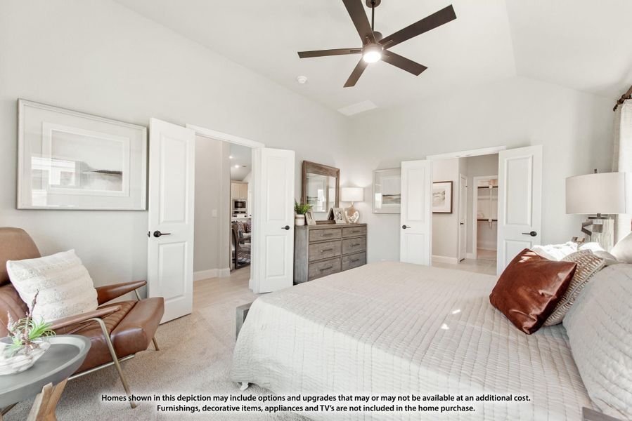 Spacious master bedroom with ceiling fan, carpet flooring, and doors leading to walk-in closet and bathroom.