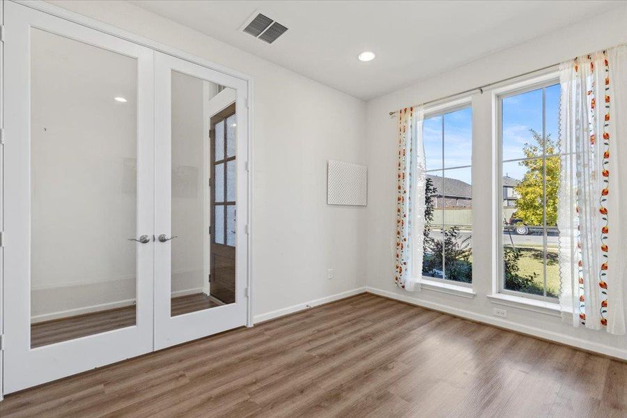 Spare room featuring french doors, plenty of natural light, wood finished floors, and recessed lighting Spare room featuring french doors, plenty of natural light, wood finished floors, and recessed lighting