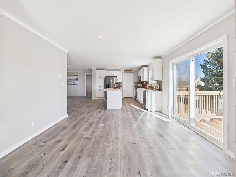 Kitchen & Family Room View – The heart of the home features a bright kitchen with white shaker cabinets, a center island, stainless steel appliances, and open sightlines to the spacious family room.