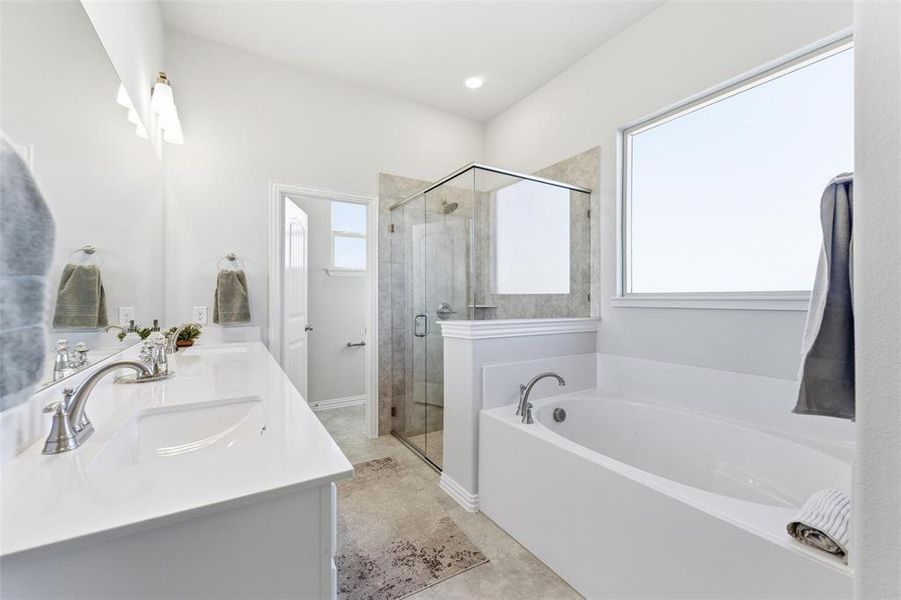 Bathroom featuring a bath, double vanity, and a stall shower