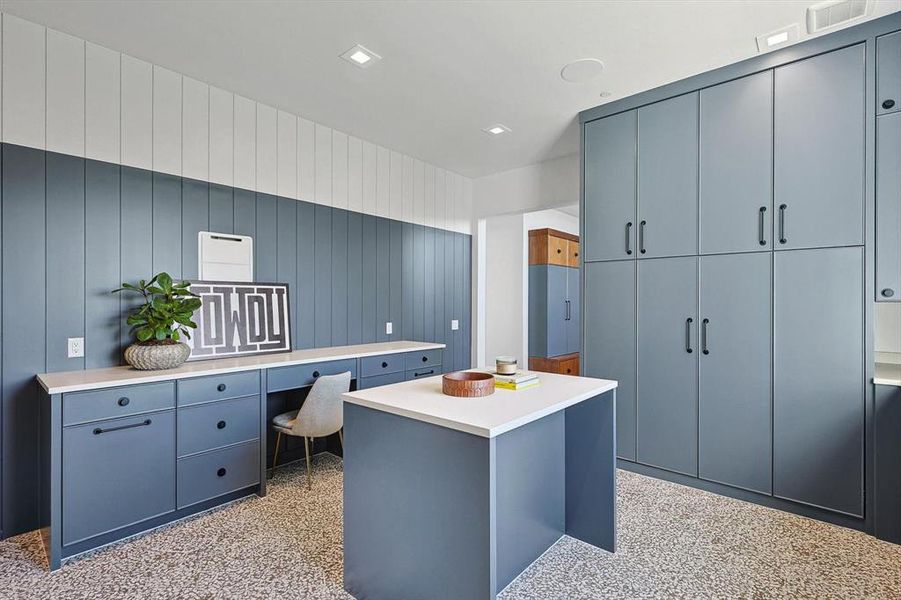 The laundry room features stylish built in cabinet storage and a home planning center.