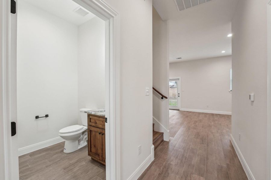 Half bathroom with visible vents, toilet, baseboards, and wood plank tile floor Half bathroom with visible vents, toilet, baseboards, and wood plank tile floor