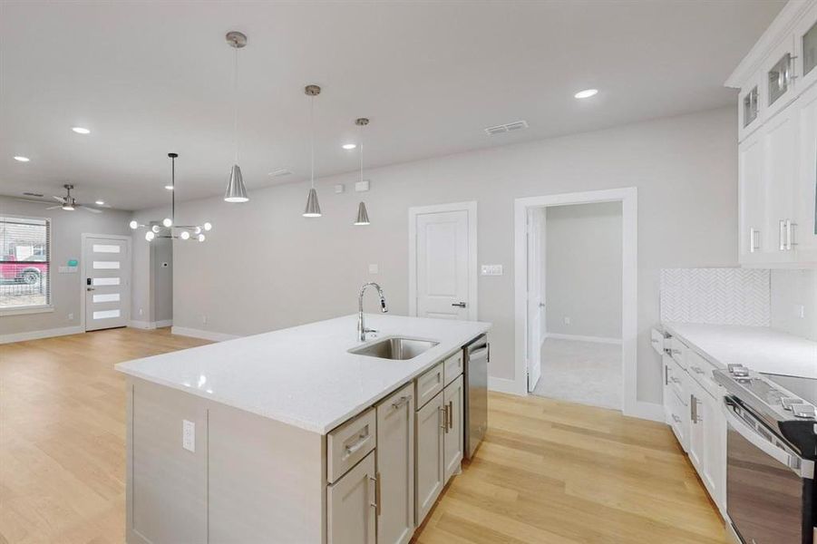 Kitchen featuring ceiling fan, sink, hanging light fixtures, an island with sink, and appliances with stainless steel finishes