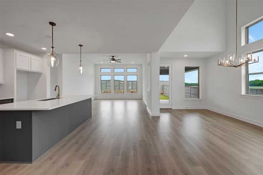 This open concept living space features light-colored flooring, high ceilings, and large windows providing natural light