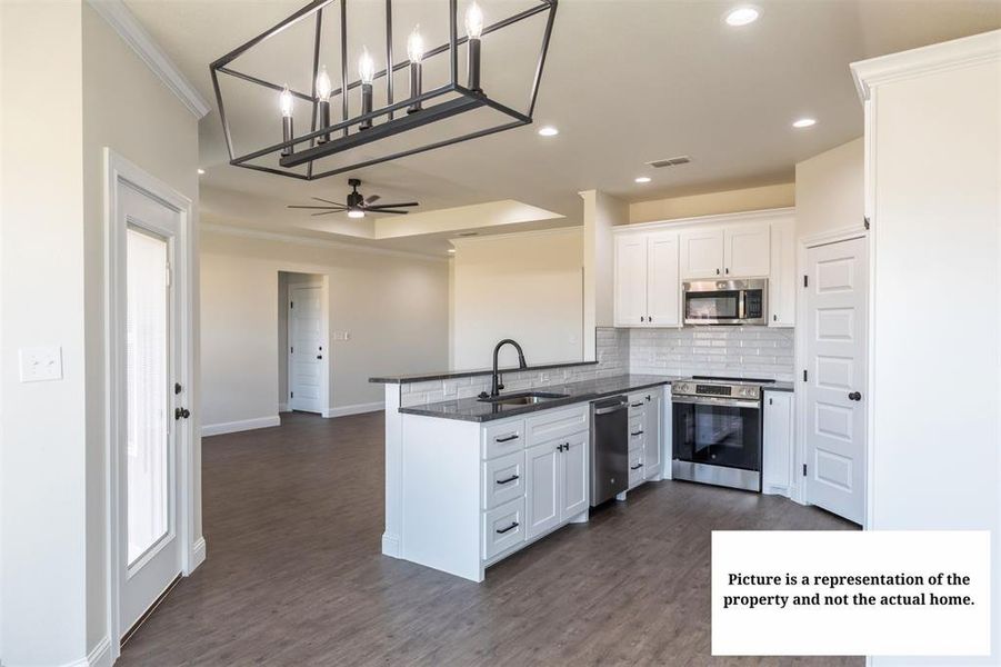 Kitchen featuring white cabinetry, dark countertops, stainless steel appliances, and a subway tile backsplash
