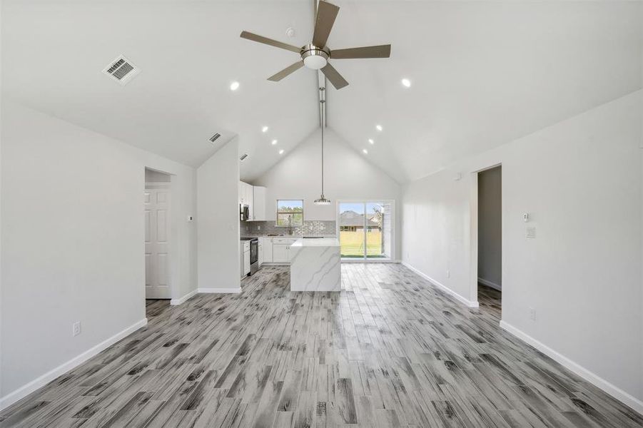 Unfurnished living room with ceiling fan, light hardwood / wood-style flooring, and lofted ceiling