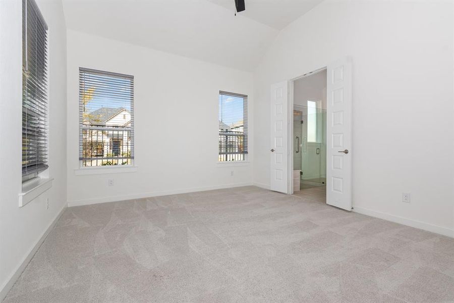 Unfurnished bedroom featuring light carpet, vaulted ceiling, ceiling fan, and ensuite bath Unfurnished bedroom featuring light carpet, vaulted ceiling, ceiling fan, and ensuite bath