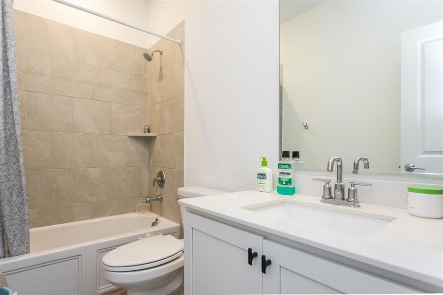 Full bathroom featuring vanity, shower / bath combination with curtain, and toilet