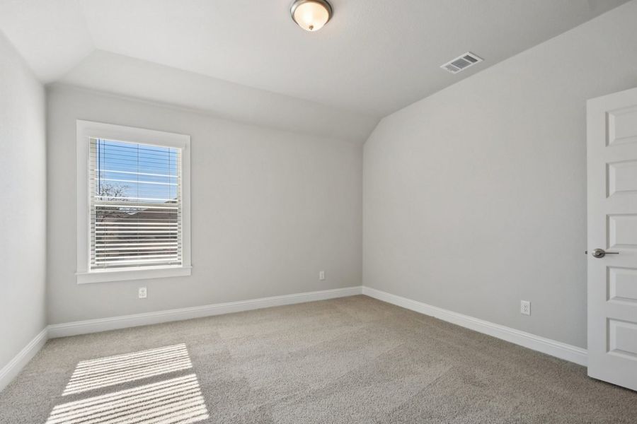 Image of a bedroom with light grey walls, tan carpeting, white trim and a window