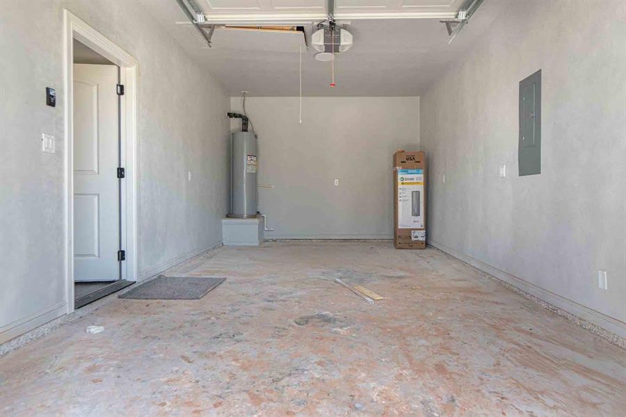 Garage with electric water heater, electric panel, and a garage door opener Garage with electric water heater, electric panel, and a garage door opener