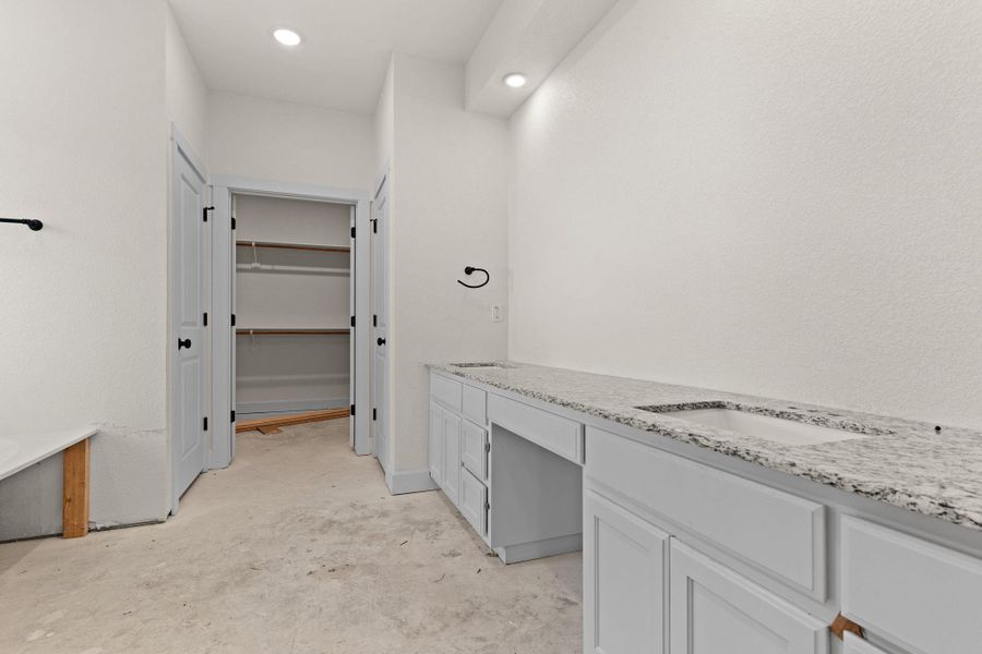 Full bathroom with double vanity, unfinished concrete floors, a spacious closet, and recessed lighting Full bathroom with double vanity, unfinished concrete floors, a spacious closet, and recessed lighting