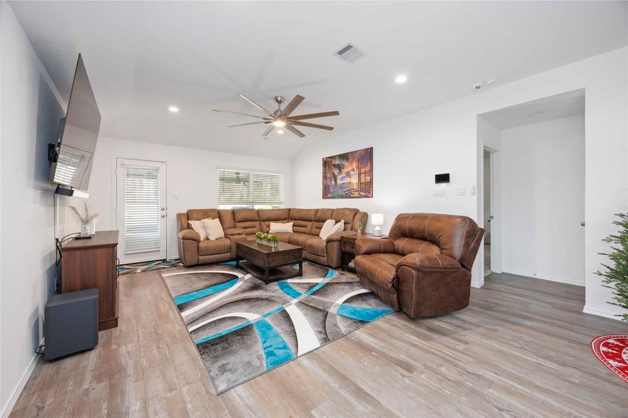 Living Room – Main Gathering SpaceSpacious and inviting living area featuring vaulted ceilings, recessed lighting, and a modern ceiling fan. Large windows and a glass door provide natural light and easy access to the backyard, while the open layout creates an ideal setting for everyday living, relaxing, or entertaining. Living Room – Main Gathering SpaceSpacious and inviting living area featuring vaulted ceilings, recessed lighting, and a modern ceiling fan. Large windows and a glass door provide natural light and easy access to the backyard, while the open layout creates an ideal setting for everyday living, relaxing, or entertaining.