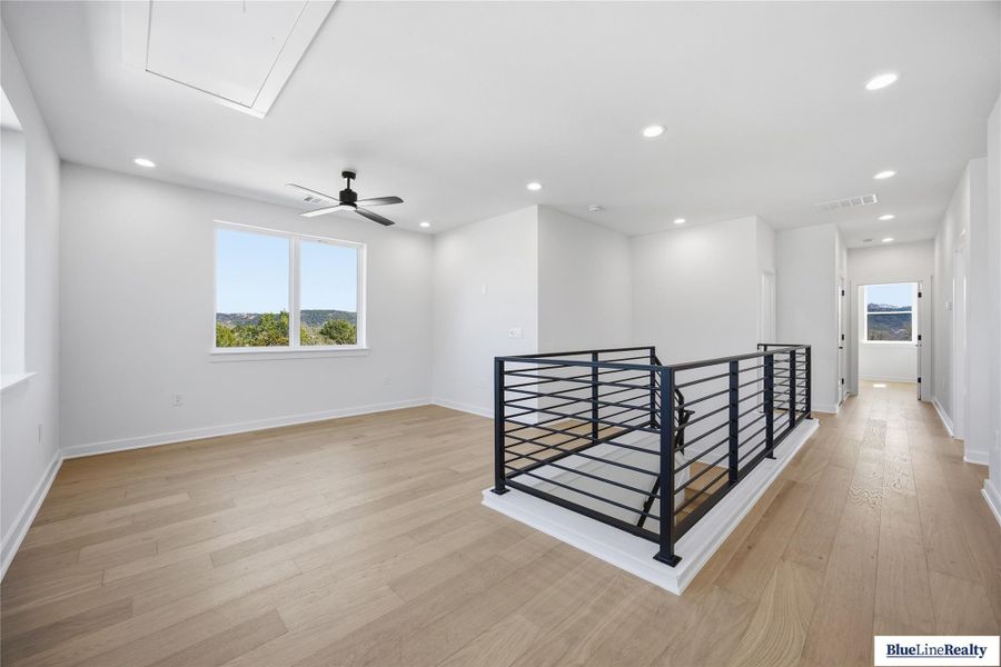 Hallway featuring an upstairs landing, recessed lighting, and light wood-style floors