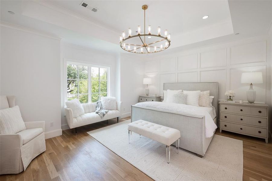 Bedroom with wood-type flooring, crown molding, a raised ceiling, and a chandelier