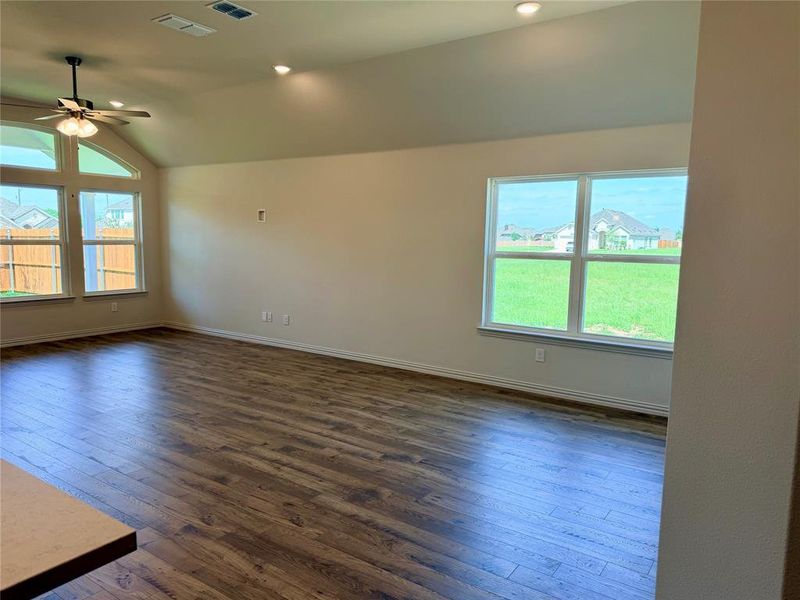 Spacious interior featuring wood-finish flooring, vaulted ceilings, recessed lighting, and a ceiling fan