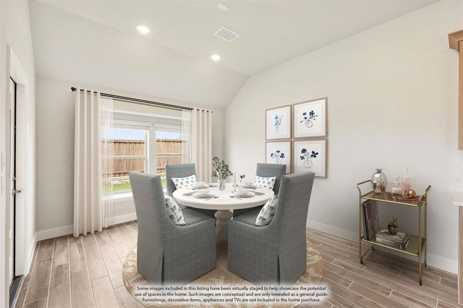 Dining room with round white table, four gray chairs, vaulted ceiling, and wood-look tile floors
