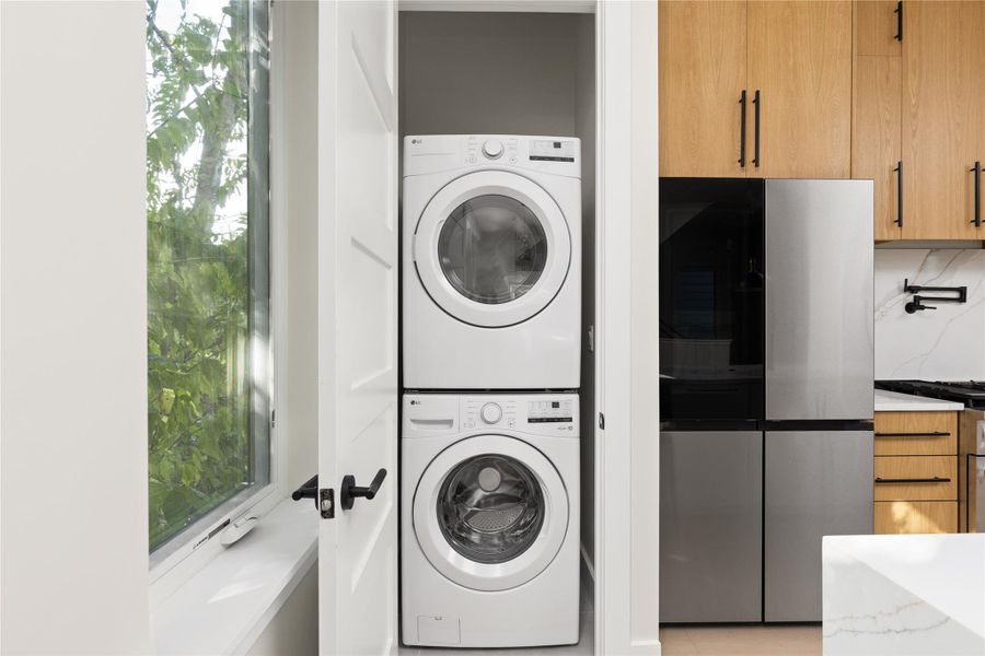 A stacked laundry setup integrates smoothly within a closet adjacent to the kitchen.