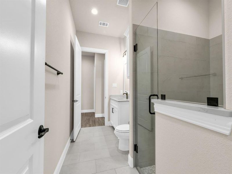 Bathroom with tile patterned floors, vanity, toilet, and a shower with door