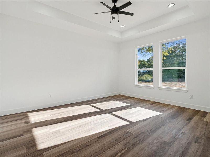 Spare room featuring ceiling fan, wood-type flooring, and a raised ceiling