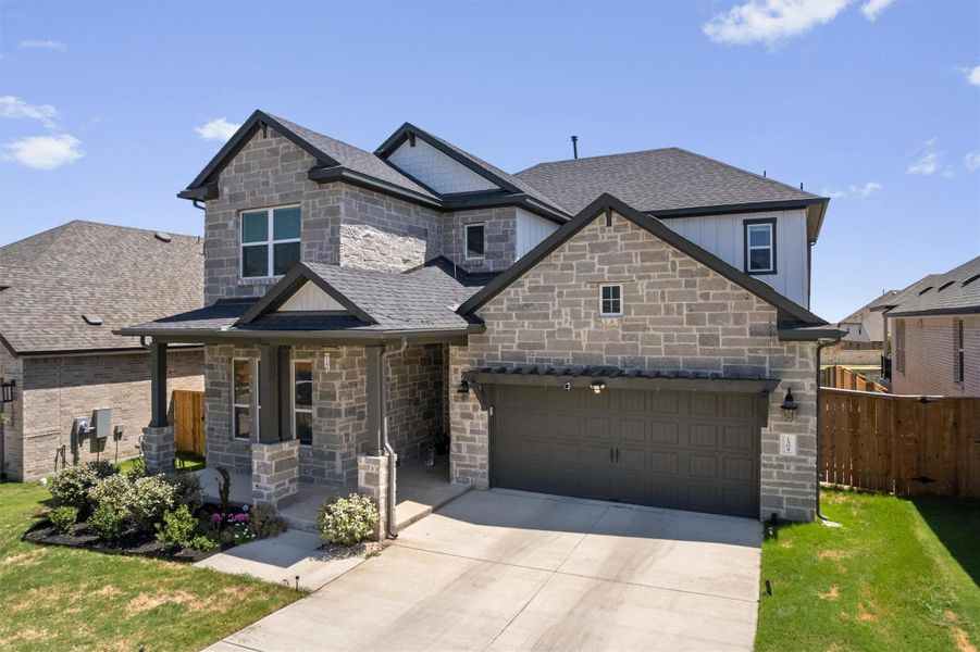 Multi-textured stone walls, multiple gables, and a wide driveway create a striking street presence.